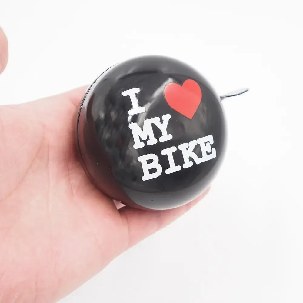 Dviračio skambutis „I love my bike“ su raudona rankena ir juodu korpusu, pritvirtintas prie dviračio vairo.