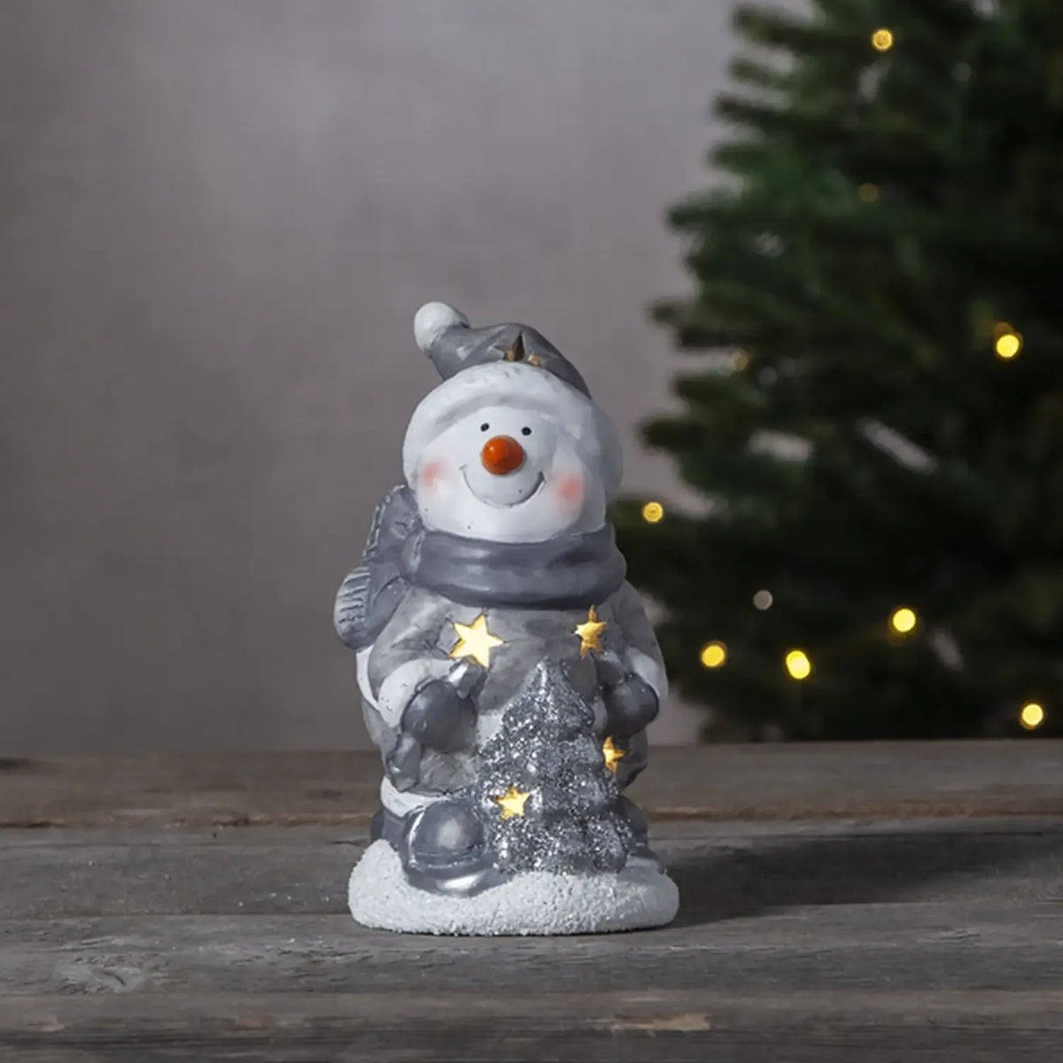 LED dekoracija „Besmegenis su eglute“, 15x9 cm, šviečianti Kalėdų dekoracija su sniego seniu ir eglute.