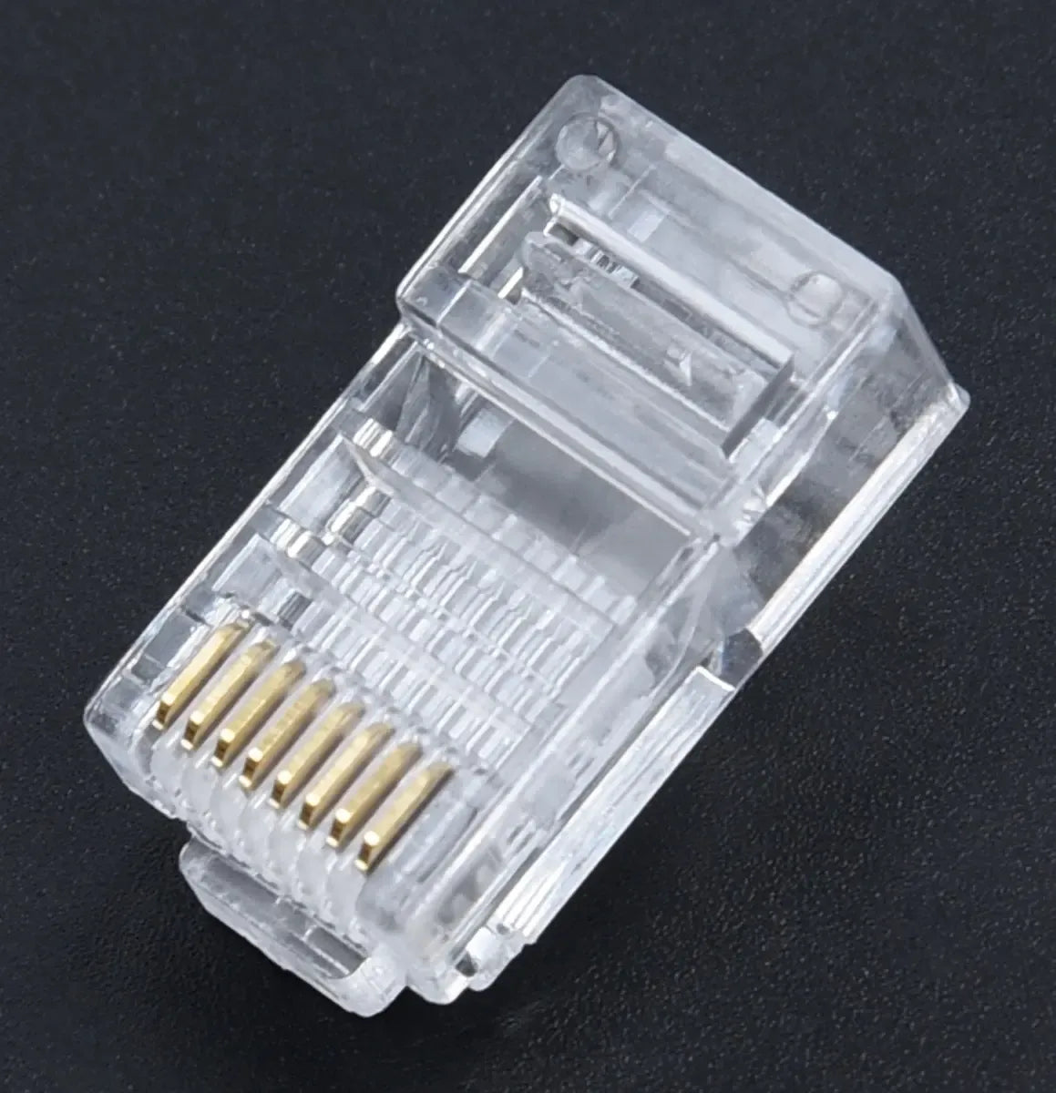 RJ-45 8P8C tinklo jungtis interneto kabeliui, padėtas ant balto fono, su aiškiai matomomis kontaktų eilėmis ir plastikiniu korpusu.